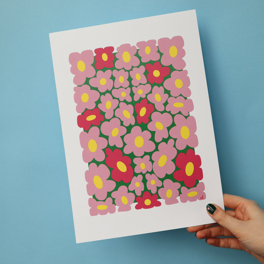 A printed artwork featuring a whimsical pattern of wobbly pink daisies on a blue background