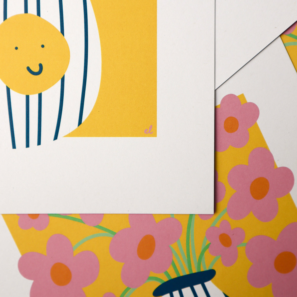 Bright colourful art prints stacked on top of each other, prints show a striped vase with pink daisies